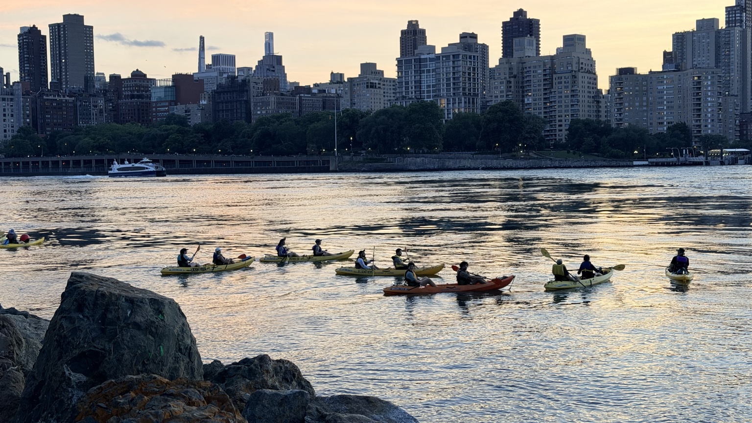 Kayakers on the East River at dusk, New York skyline behind